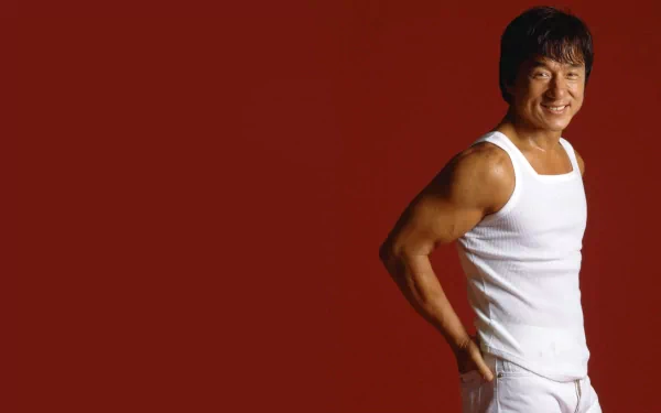HD wallpaper featuring celebrity Jackie Chan against a red background, wearing a white sleeveless shirt and pants, smiling confidently.