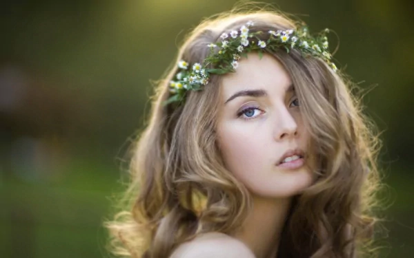 A high-definition desktop wallpaper featuring a woman with flowing hair and a floral headband, captured in a serene and natural outdoor setting.