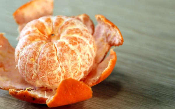 HD PC desktop wallpaper featuring a close-up of a peeled mandarin with vibrant orange skin against a wooden surface.