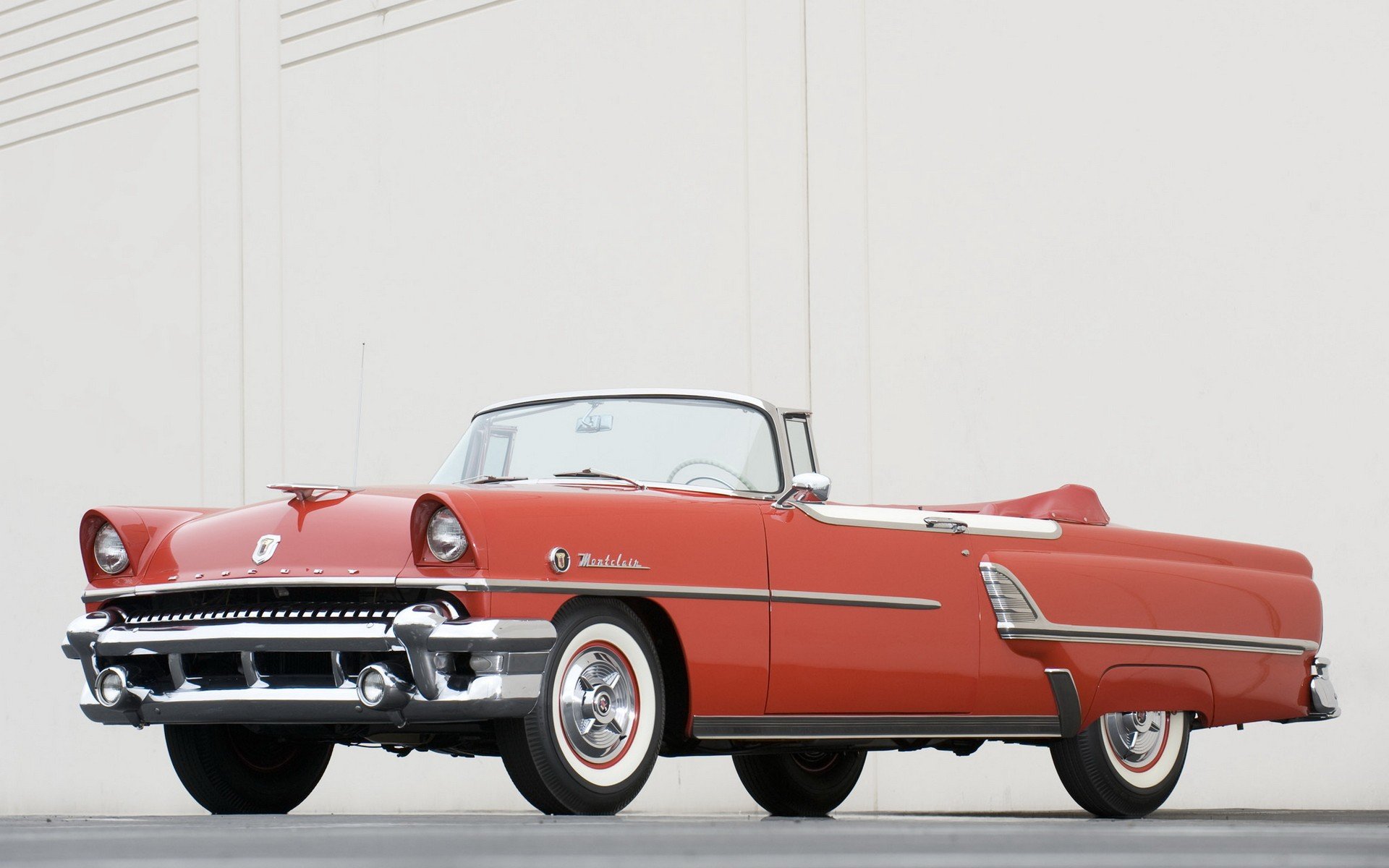 HD PC desktop wallpaper and background: red Mercury Montclair convertible with 1950s chrome trim and whitewall tires against a pale wall.