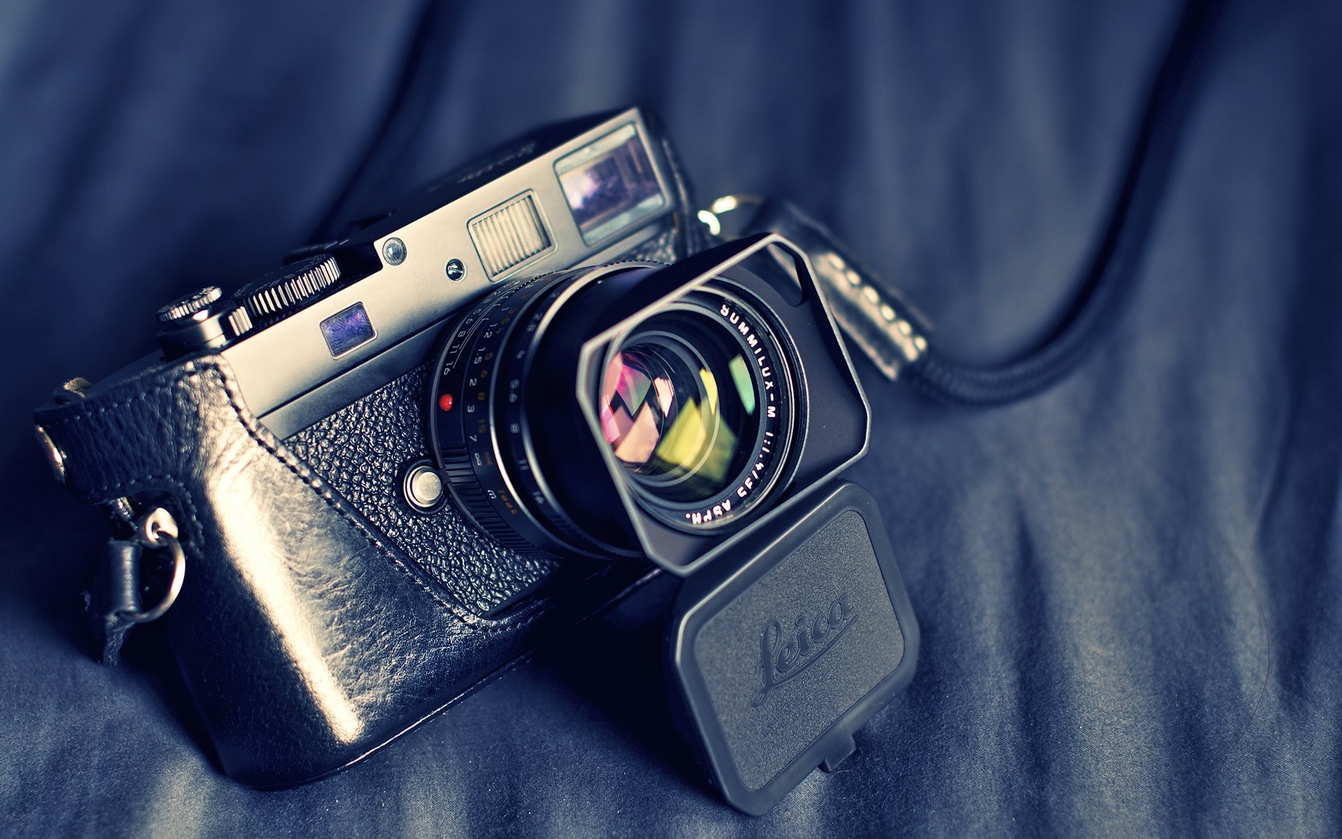 HD desktop wallpaper featuring a detailed close-up of a man-made Leica camera resting on a dark fabric background.