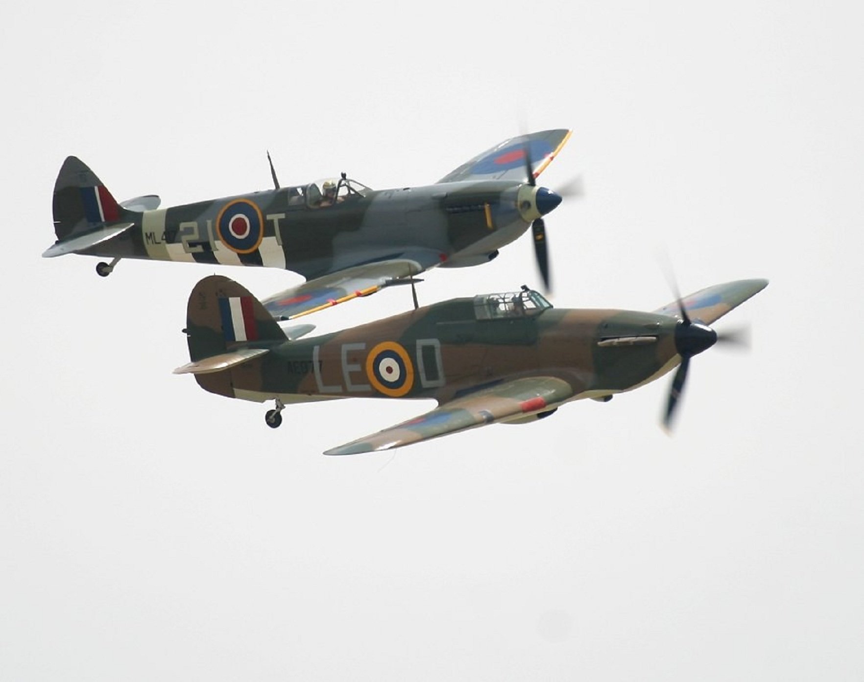 Two military aircraft fly in formation against a cloudy sky, showcasing their distinctive markings. This HD image serves as an impressive desktop wallpaper.