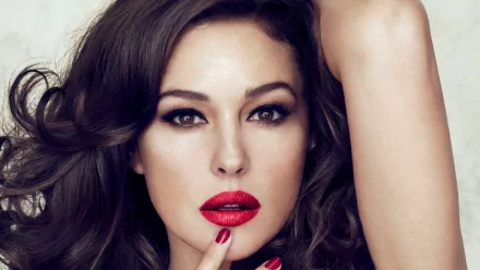 A stunning HD desktop wallpaper featuring Monica Bellucci with glamorous makeup and tousled hair, highlighting her captivating gaze and bold red lips.