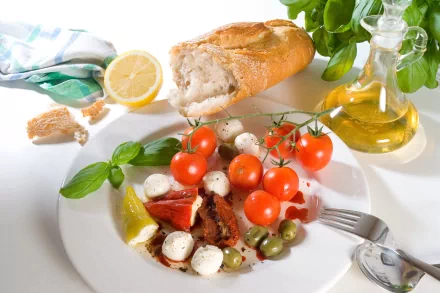 A 4K Ultra HD desktop wallpaper featuring a fresh meal with bread, cherry tomatoes, mozzarella, olives, basil, lemon, and olive oil on a white plate.