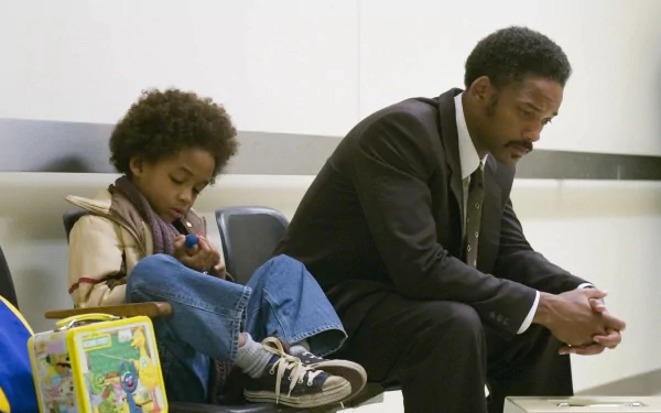 A poignant scene from The Pursuit of Happyness, featuring Jaden Smith and Will Smith. They sit together, reflecting their characters' struggles and bond in a moment of quiet intensity.