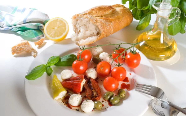 A 4K Ultra HD desktop wallpaper featuring a fresh meal with bread, cherry tomatoes, mozzarella, olives, basil, lemon, and olive oil on a white plate.