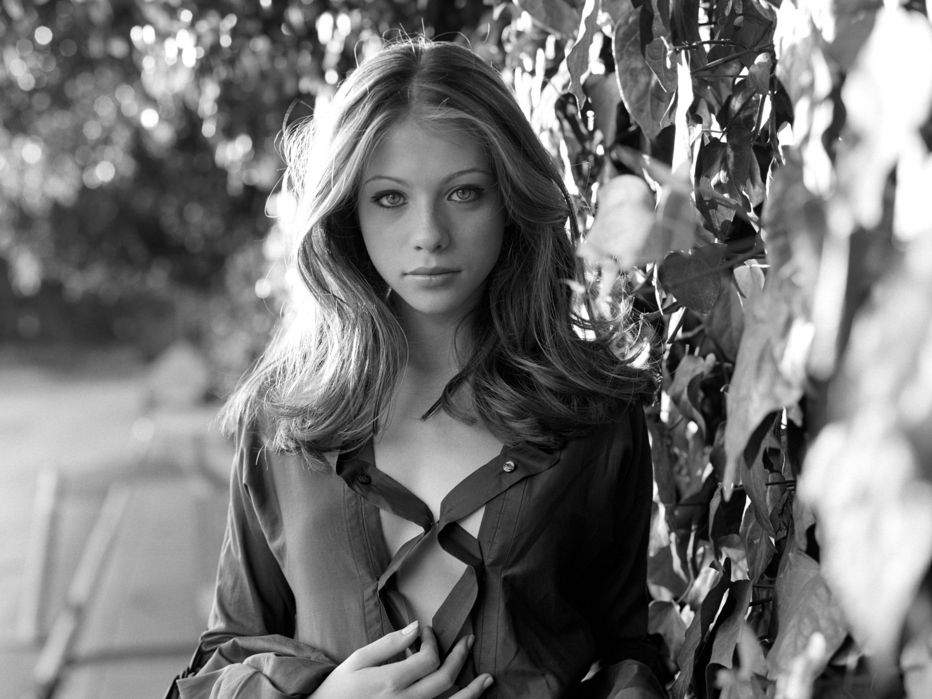 Black and white 4K Ultra HD portrait of American actress Michelle Trachtenberg, set against a natural outdoor background.