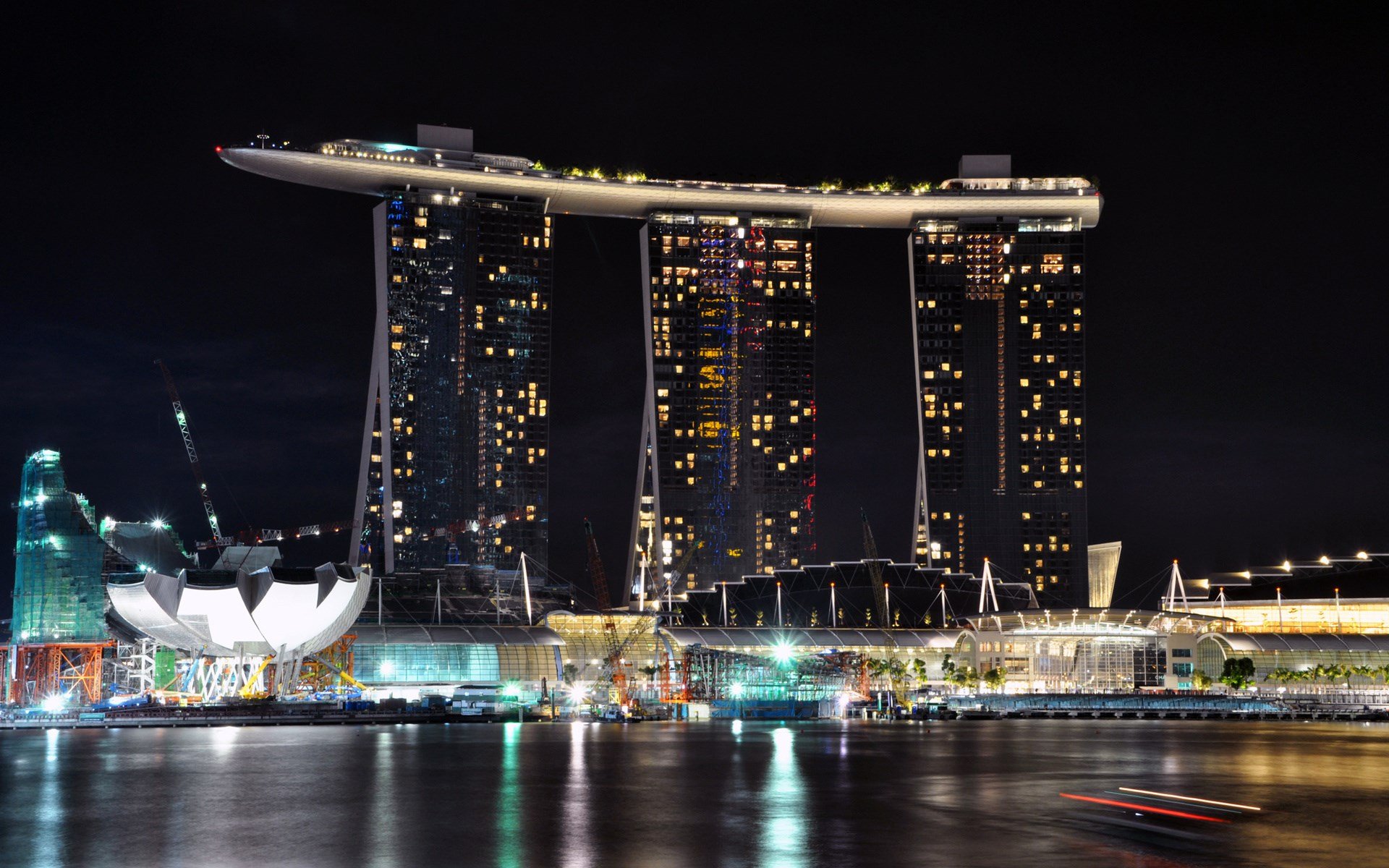 HD PC desktop wallpaper background: Singapore's man-made Marina Bay Sands lit at night, its three towers and rooftop SkyPark reflected on the calm bay.