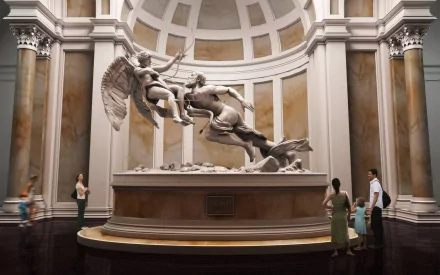 HD PC desktop wallpaper showcasing a detailed man-made statue of winged figures engaged in dynamic movement within an elegant, columned gallery space.