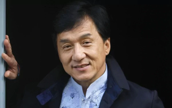 HD wallpaper of celebrity Jackie Chan, featuring a close-up shot of him smiling in a dark jacket and white shirt.