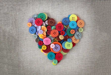 A colorful arrangement of buttons forms a heart shape against a textured background, creating an artistic HD desktop wallpaper.