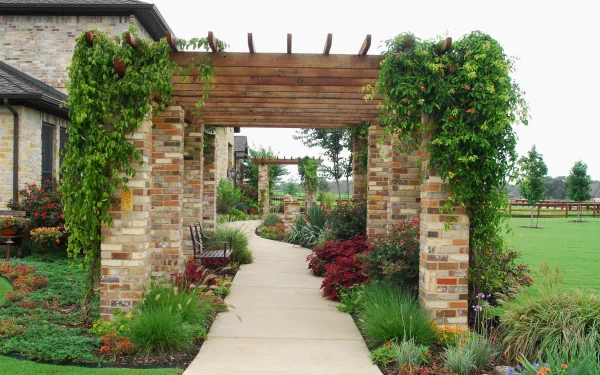 HD desktop wallpaper featuring a beautifully landscaped garden pathway with lush greenery, flowers, and vine-covered brick pergolas, set in front of a charming house.