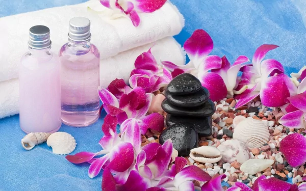 A serene still life featuring stacked stones, vibrant orchids, and seashells, complemented by spa essentials like towels and bottles, set against a tranquil blue background.