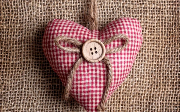 Artistic 4K Ultra HD wallpaper featuring a red gingham fabric heart ornament with a button and twine bow on a textured burlap background.