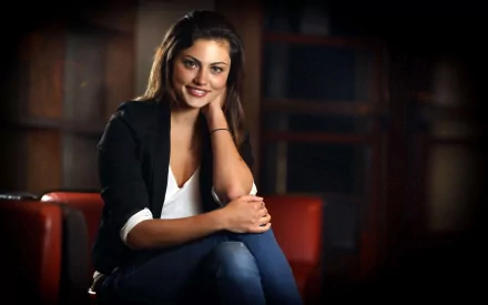 HD PC desktop wallpaper featuring celebrity Phoebe Tonkin seated, smiling gently against a softly blurred dark background.