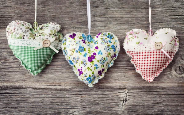 Artistic hearts made of floral and gingham fabric hang against rustic wood, captured in stunning 4K Ultra HD for a charming PC desktop wallpaper.