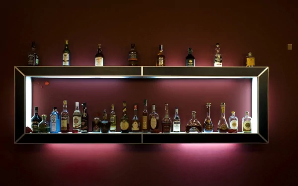 A sleek display shelf featuring a variety of liquor bottles against a deep-colored wall, creating an atmospheric setting for food and drink enthusiasts. HD desktop wallpaper background.