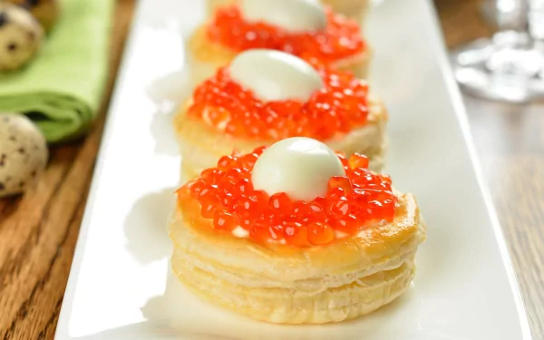 HD desktop wallpaper featuring close-up of elegant appetizers topped with vibrant red caviar and a creamy white garnish on a white rectangular plate.