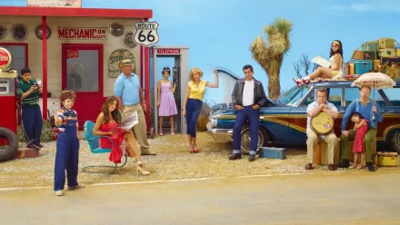 HD wallpaper of Modern Family cast posing playfully by a roadside gas station with a classic car and Route 66 sign.