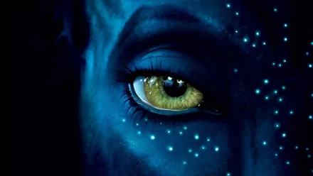 A captivating HD wallpaper featuring a close-up of an eye with vibrant yellow-green iris and blue skin, inspired by the film Avatar, showcasing intricate details and ethereal patterns.
