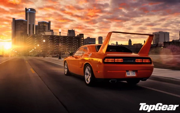 HD desktop wallpaper of a vibrant orange sports car on the highway at sunset with a city skyline ahead, branded with Top Gear.