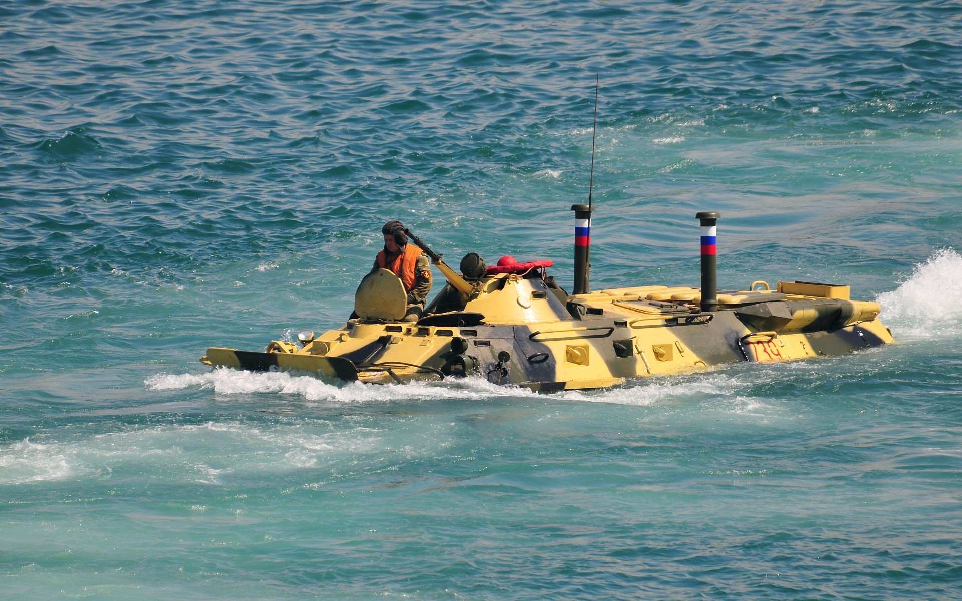 HD PC desktop wallpaper showing a military amphibious vehicle moving through clear blue water.