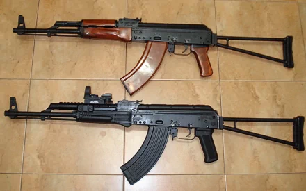 HD PC desktop wallpaper of two man-made AKM assault rifles laid side by side on a tiled floor, one with wooden furniture and one with black synthetic parts