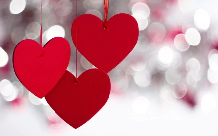 HD PC desktop wallpaper featuring three red hanging hearts against a softly blurred background, celebrating Valentine's Day holiday.