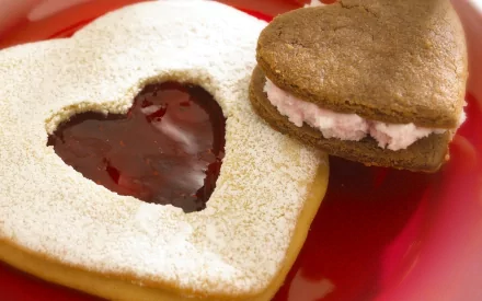 HD PC desktop wallpaper featuring heart-shaped cookies, one with powdered sugar and jam, the other with a creamy filling, highlighting delicious food details.