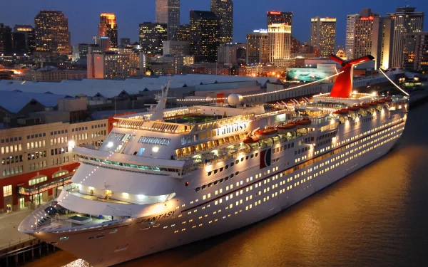 A stunning HD wallpaper of the Carnival Fantasy cruise ship docked at night, illuminated against the skyline of a vibrant city. A captivating backdrop for your desktop.