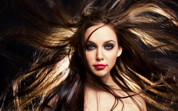 A striking HD wallpaper featuring a woman with cascading hair and bold makeup, exuding confidence and style against a dark background.