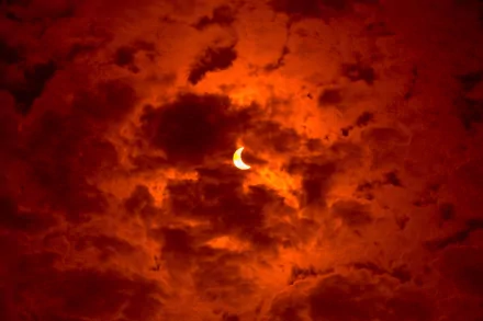 HD desktop wallpaper showing a glowing crescent moon partially hidden by dramatic red and orange clouds in the night sky, highlighting natural celestial beauty.