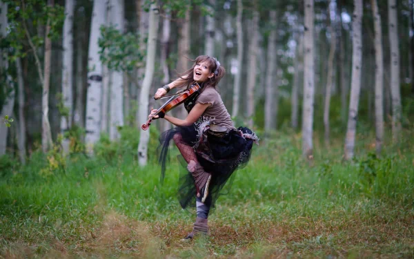 A joyful musician, Lindsey Stirling, plays the violin amid a lush forest backdrop, embodying a vibrant spirit in this 4K Ultra HD desktop wallpaper.