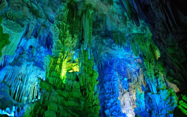 Vibrant blue and green illuminated formations inside Reed Flute Cave, showcasing stunning natural rock structures in an HD nature desktop wallpaper.