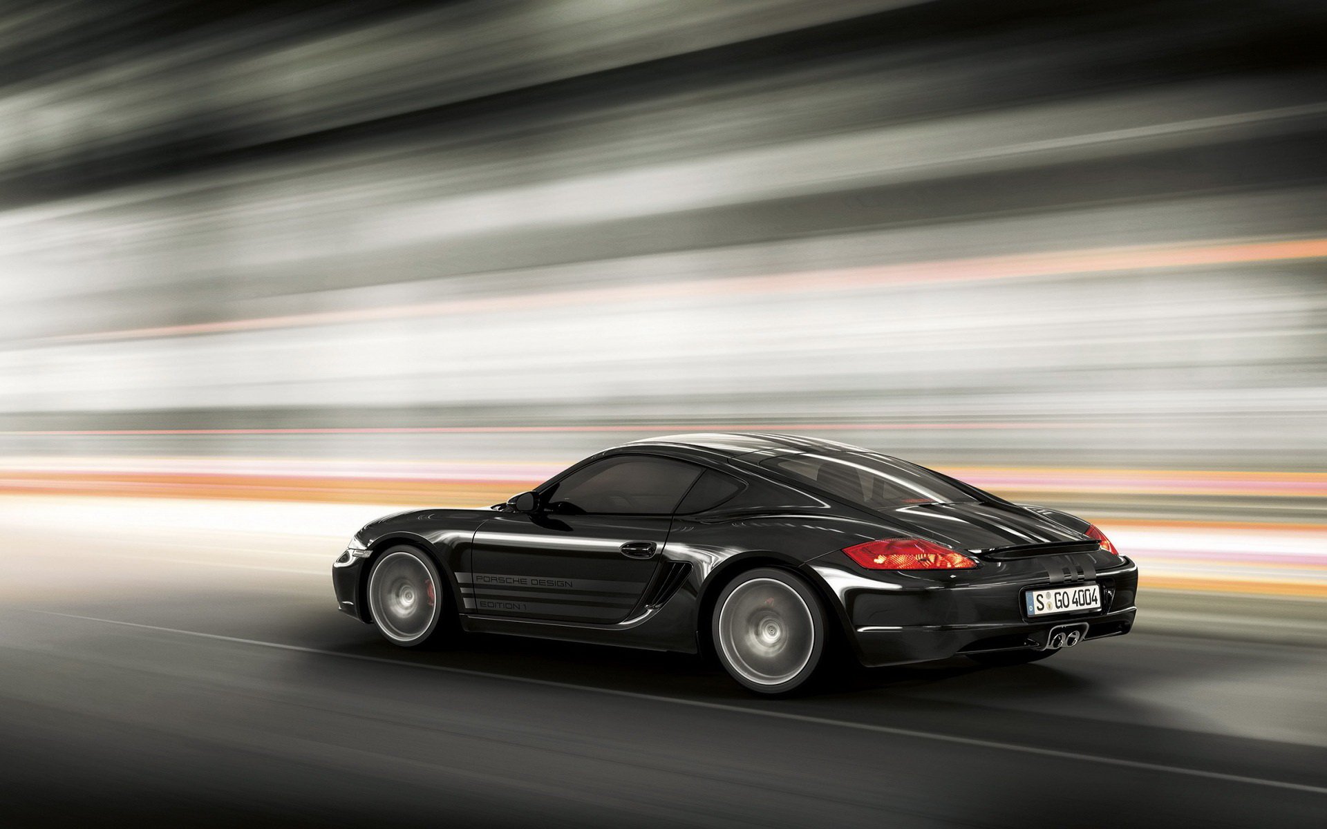 Black Porsche Cayman S speeding on a blurred race track, captured in high definition as a dynamic PC desktop wallpaper and background.