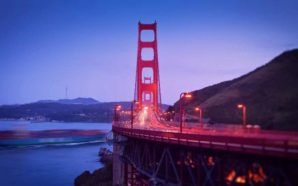 HD desktop wallpaper featuring the Golden Gate Bridge at dusk, showcasing vibrant lights and calm waters under a clear sky.