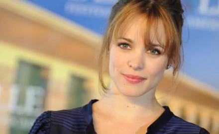 Rachel McAdams poses for a photo, showcasing her signature look with soft waves and a subtle smile, set against a colorful backdrop. This HD image serves as an elegant desktop wallpaper.