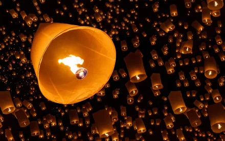 A stunning HD wallpaper featuring a glowing candle lantern surrounded by numerous floating candles, creating a mesmerizing ambiance against a dark background.