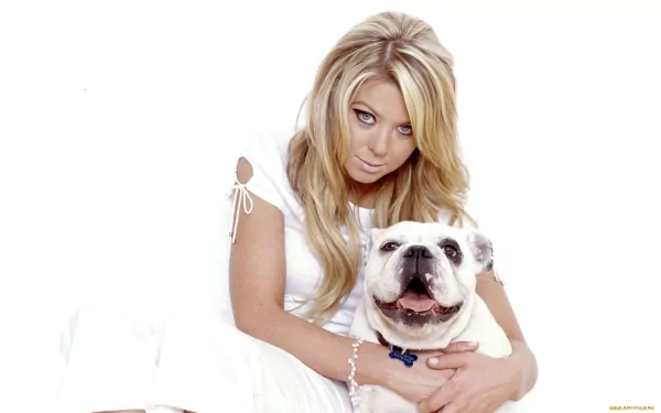 Tara Reid poses with a smiling bulldog, both looking at the camera. The image serves as a stylish HD wallpaper, capturing a warm and playful moment.