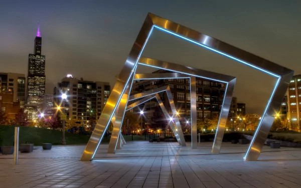 Illuminated geometric metal sculptures at night in Mary Bartelme Park, Chicago, Illinois, with city buildings and the Willis Tower in the background.