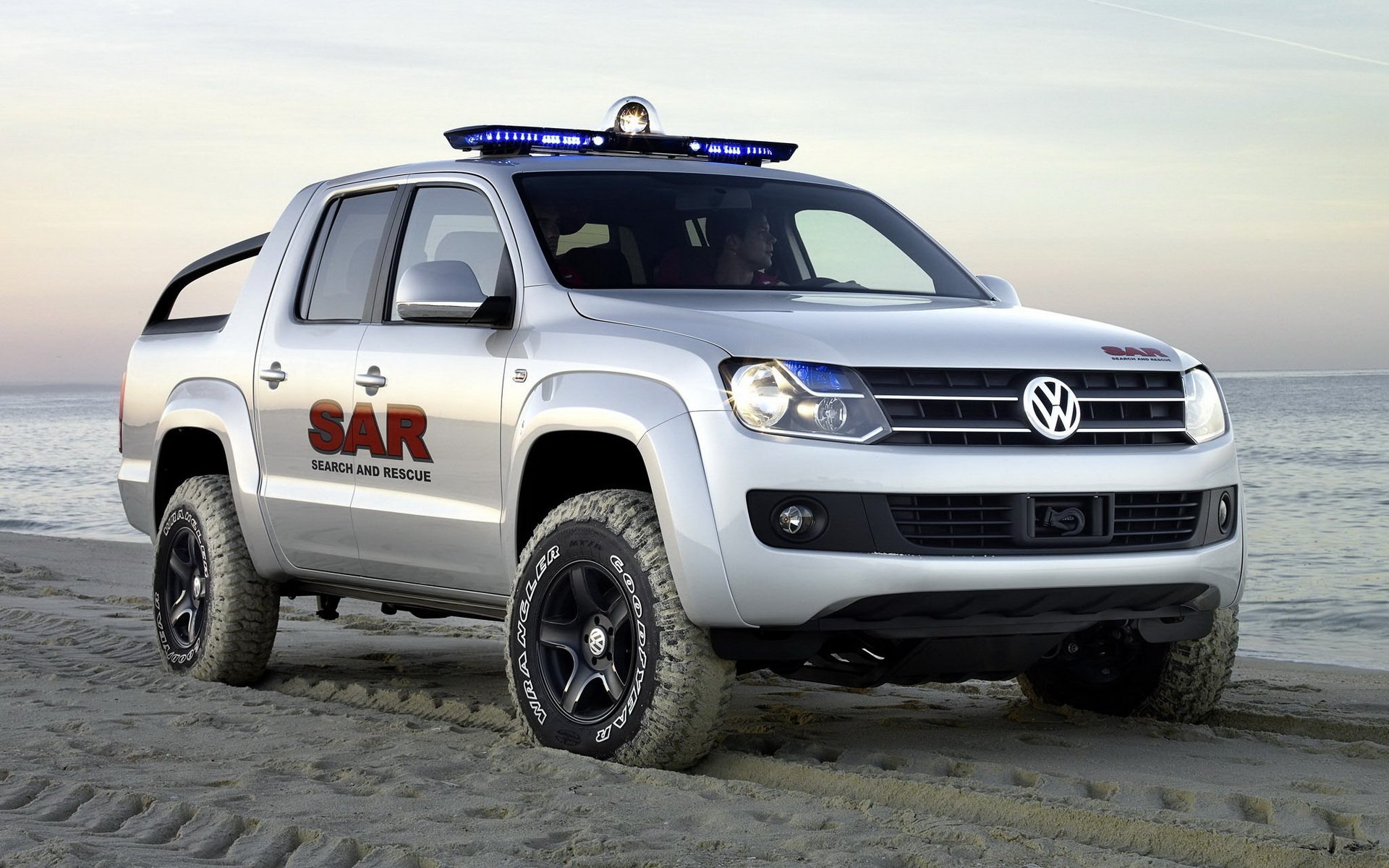 HD desktop wallpaper featuring a Volkswagen Amarok SAR vehicle parked on a sandy beach at sunset.