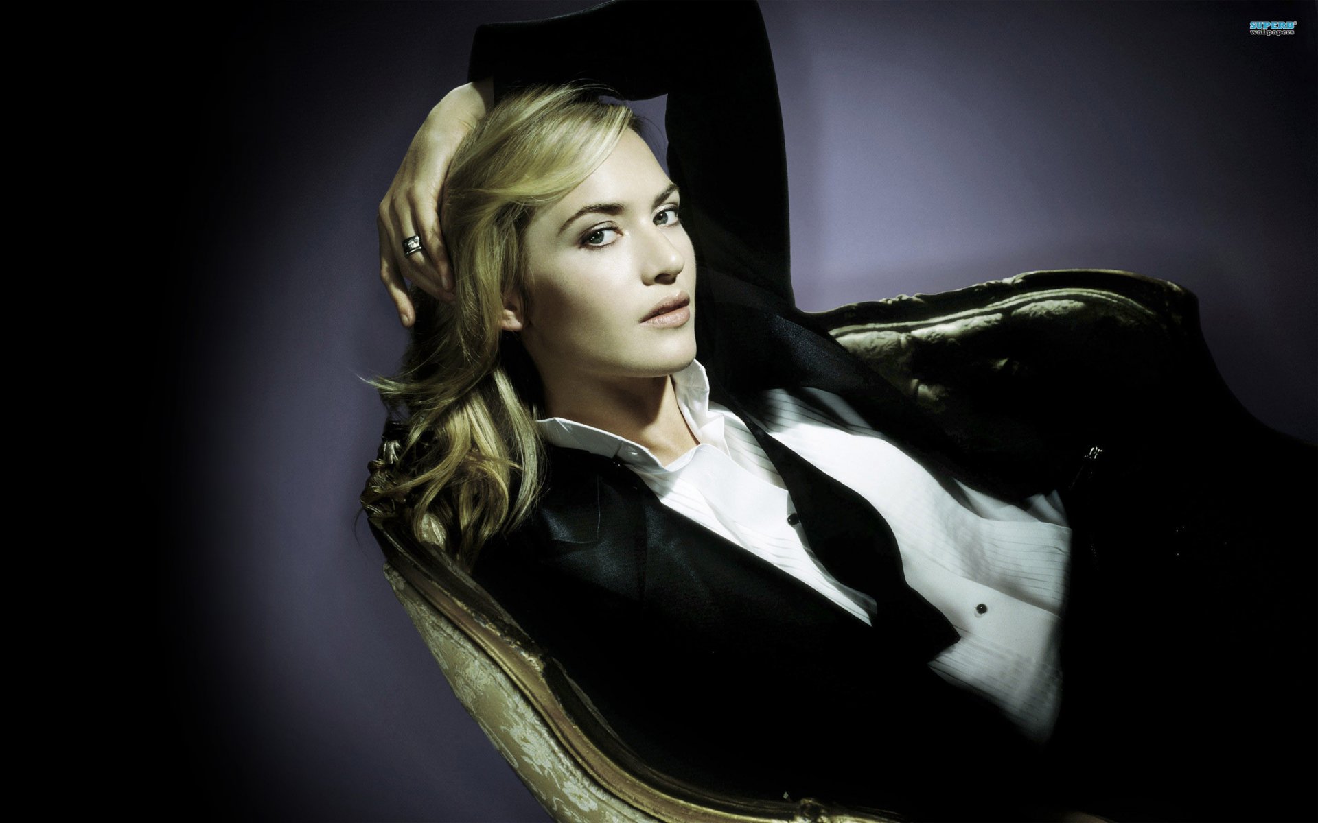 HD PC desktop wallpaper featuring celebrity Kate Winslet reclining on a dark, vintage chair against a soft, muted background.