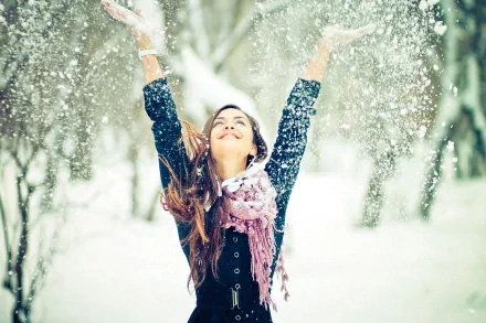 A joyful woman with outstretched arms celebrates in a snowy landscape, capturing a vibrant mood. This HD desktop wallpaper radiates happiness and winter charm.