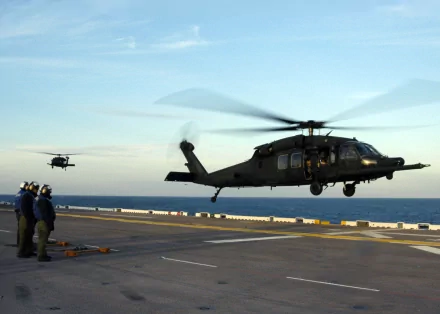 Military Sikorsky UH-60 Black Hawk helicopters hover above a naval deck at sea, captured in an HD PC desktop wallpaper and background.