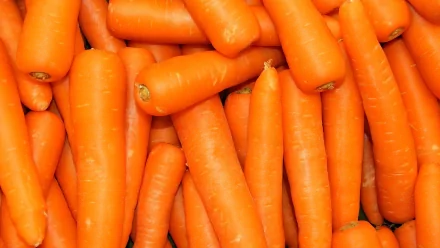 An HD desktop wallpaper featuring vibrant orange carrots stacked together, highlighting their fresh color and vegetable appeal.