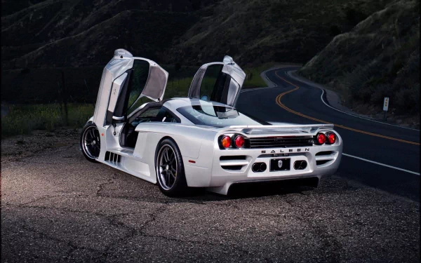 White Saleen S7 with butterfly doors open, parked on a winding road at dusk. HD PC desktop wallpaper showcasing the sleek vehicle’s design and sporty profile.