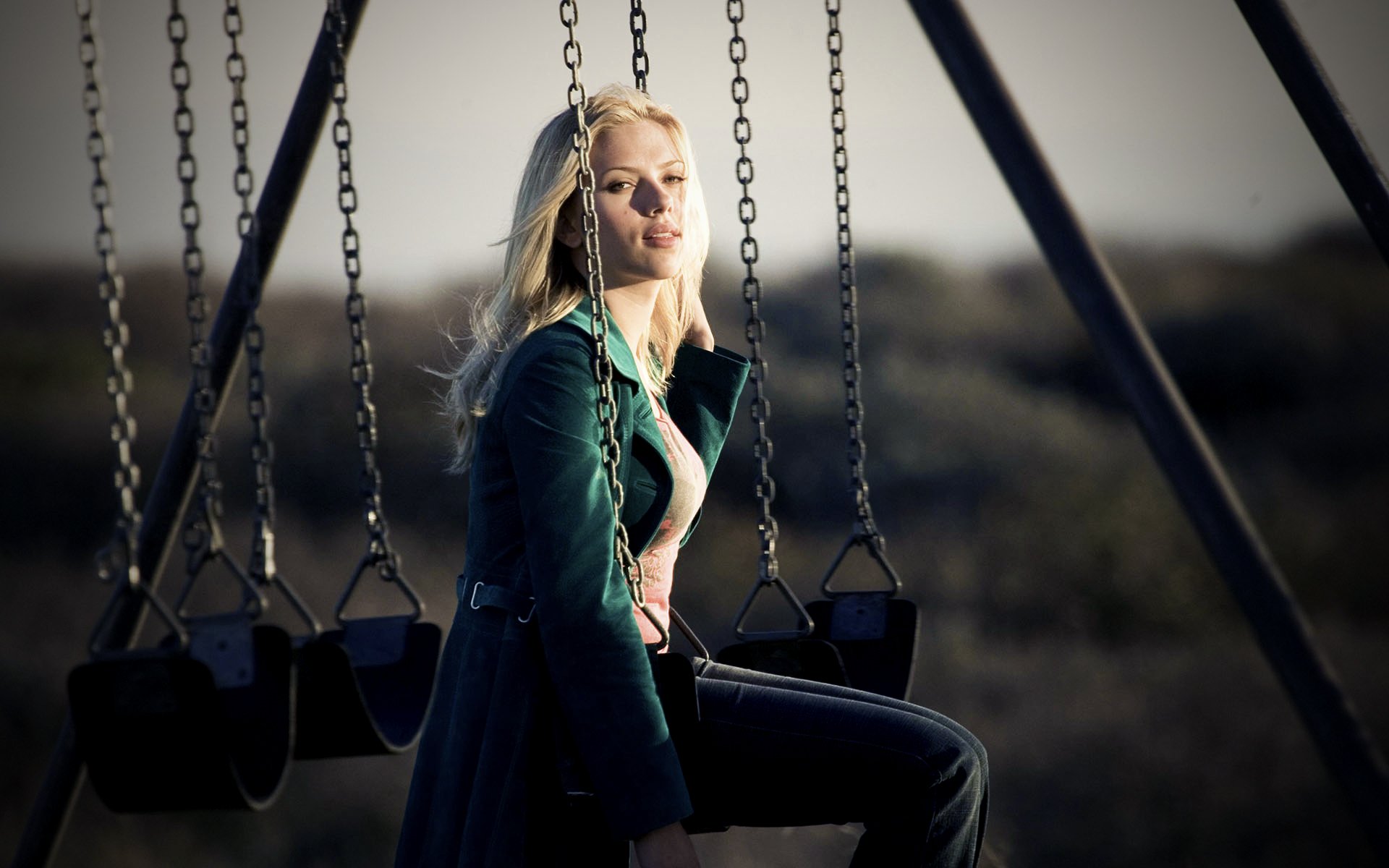 Scarlett Johansson sitting on a swing in an evocative outdoor setting, captured in a high-definition desktop wallpaper.