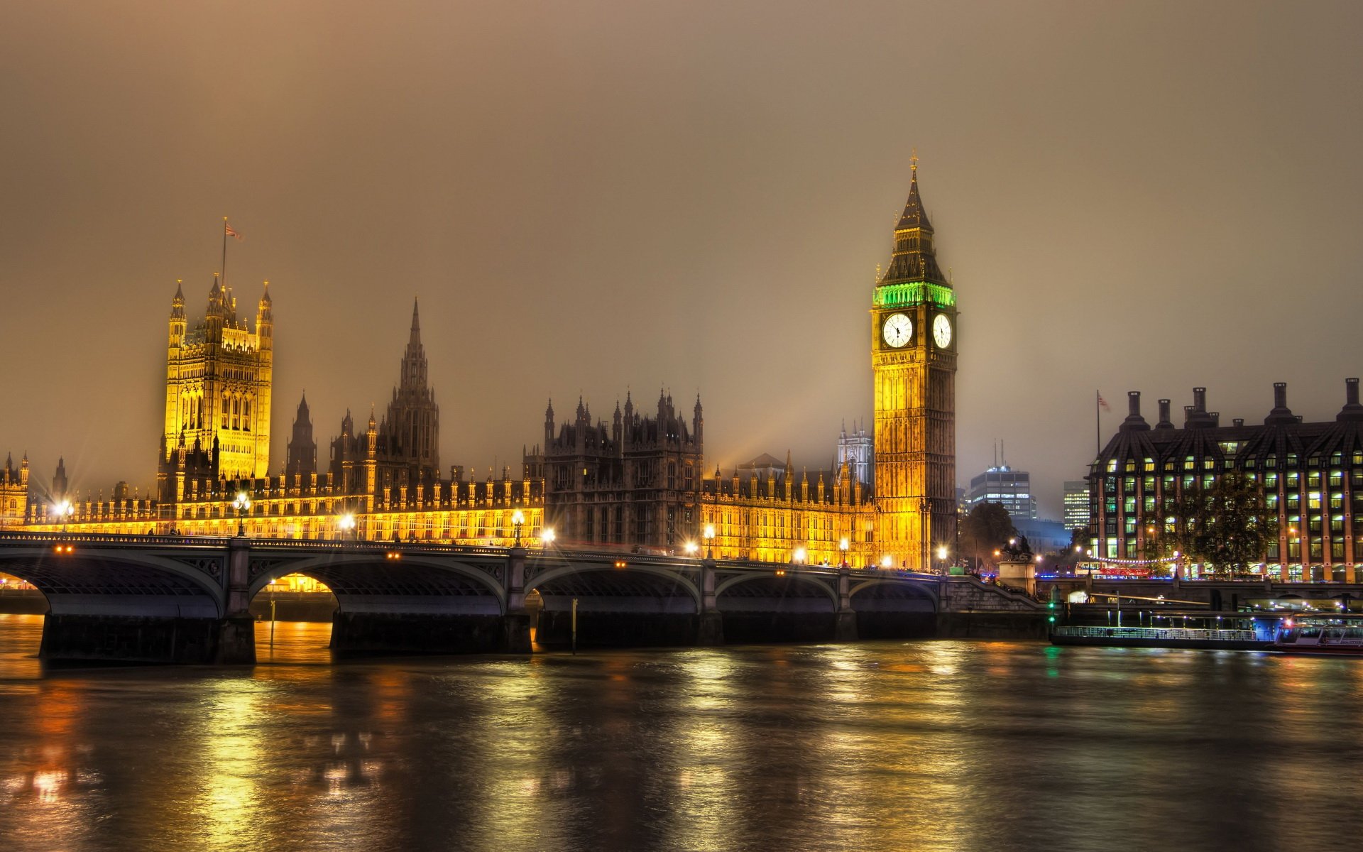 HD desktop wallpaper showing a nighttime view of Big Ben and the illuminated Houses of Parliament reflected on the River Thames in London.