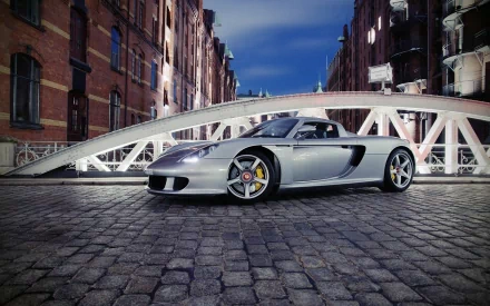 A sleek Porsche Carrera GT parked on a cobblestone street, with an elegant bridge in the background, captured in stunning HD for a striking desktop wallpaper.
