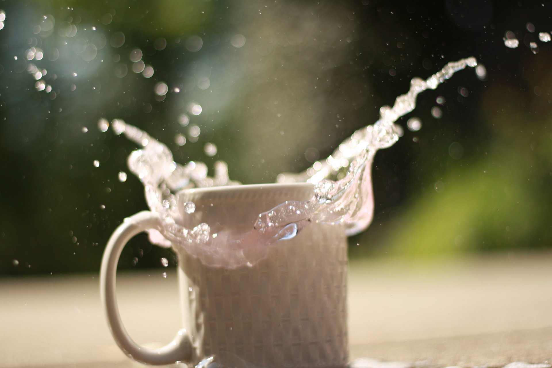 4K Ultra HD PC desktop wallpaper and background: white ceramic mug with milk splashing outward against a sunlit green bokeh backdrop, food and drink theme.